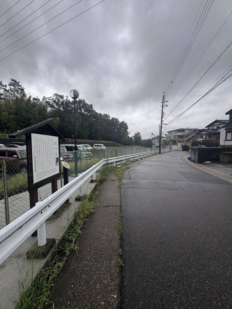 A wet road and signboard at Kamagatani under heavy cloud